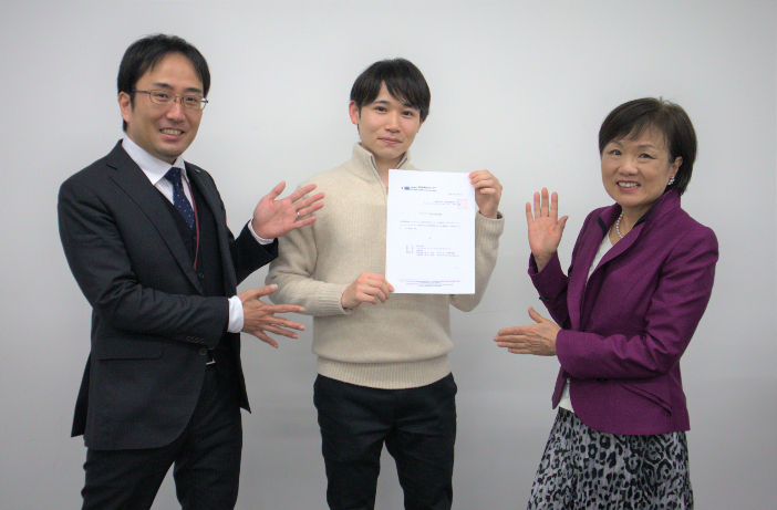 陸田さんの合格を祝う、研修申請をサポートした大砂教授（写真右）と国際交流室の久郷さん（写真左）