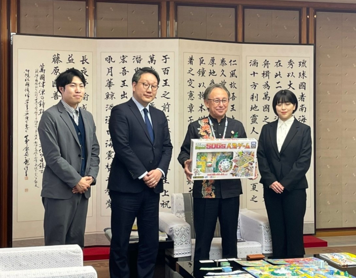 SDGs推進センターの平本督太郎所長（左から2人目）から玉城デニー知事（右から2人目）にBeyond SDGs人生ゲームを贈呈