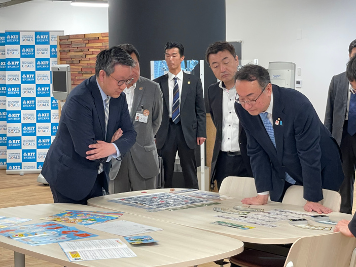 岡田大臣（写真右）に新たに開発したゲームについて解説を行う平本所長（写真左） <br>6月18日（日）ＳＤＧｓ推進センターで