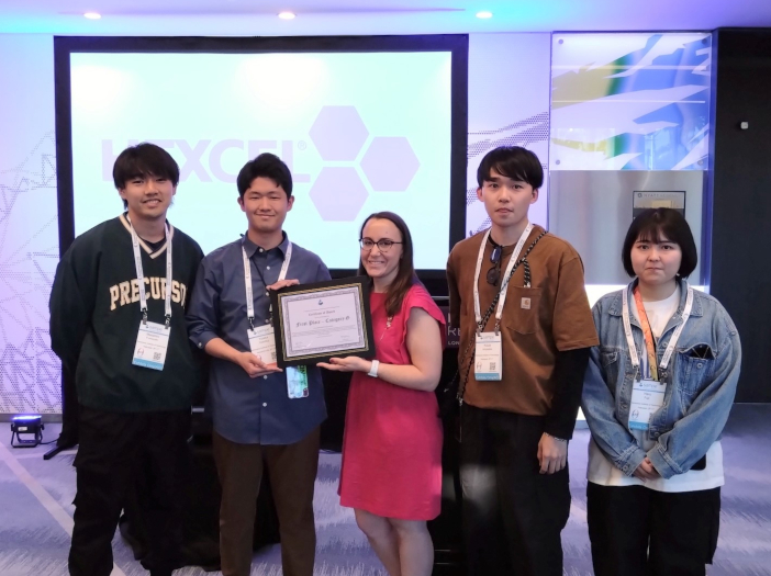 会場で司会者から授与された賞状を手にする金沢工業大学大学院チーム<br class="hidden-sp"> （左より普輪崎将寛さん、吉藤穣さん、天坂恒太さん、藤井ハルさん）