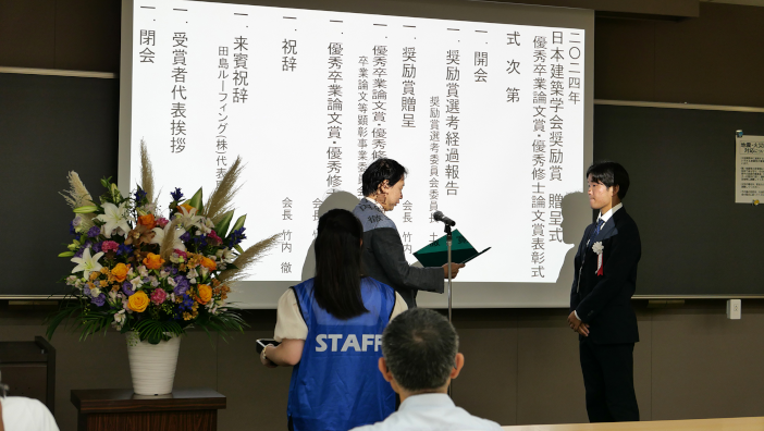 日本建築学会　竹内徹会長より表彰状を受け取る武田さん
