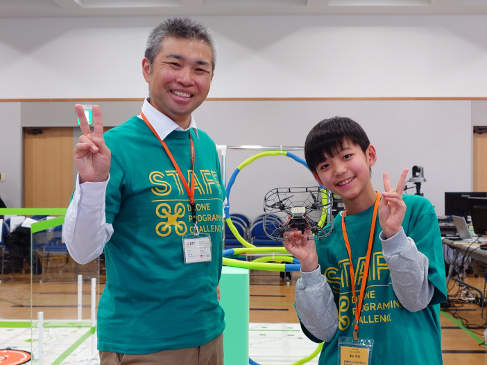 廣田 悠羽 選手（写真右）はカナザワドローンプログラミングチャレンジでのエキジビションにも出場した。写真左は大会実行委員長をつとめる金沢工業大学　河並教授
