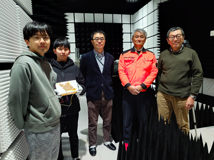 写真右から金沢工業大学 伊東健治教授、JAXA 宇宙科学研究所（ISAS) 田中孝治准教授、金沢工業大学電気・光・エネルギー応用研究センター 坂井尚貴研究員、総合研究大学院大学大学院生 中村壮児・折居遼平<br>（金沢工業大学扇が丘キャンパス内　電波無響室で）