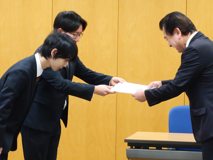 粟市長に「『住民異動届』英語マニュアル」を贈呈する平田 優大さんと浅野 翔さん