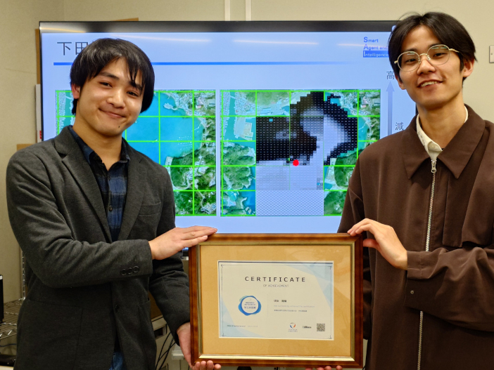 写真右から頃安さん、下川さん（2025年4月24日金道研究室で撮影）。 中央の画像は下田港全域の減衰長ヒートマップ。減衰長が小さいほど色が濃くなり（汚濁を示す）、減衰長が大きいほど色が薄くなっている（汚濁が低いことを示す）