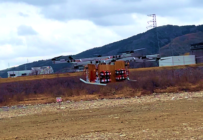 <span style="font-size: 100%">手取川河川敷にある白山ラジコンクラブのラジコン飛行場で行われた飛行試験の模様。<br class="hidden-sp"> バッテリー８個を搭載した大型ドローンは約90kgの重量となる。<br class="hidden-sp">飛行試験では、これに50kg超のおもりを積載し、見事浮上した（2025年3月6日）</span>