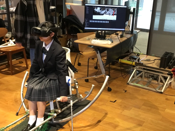 VR型チェアスキーシミュレータを体験する生徒。<br>バーチャル空間とリアル空間が連動して迫力あるスキーが楽しめる。金沢工業大学チャレンジラボを拠点に分野を超えて学生が集まるクラスター研究室で開発された