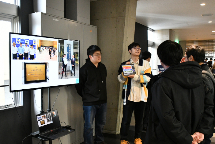 情報工学科 向井宏明研究室では、金沢工業大学サイバー防犯ボランティアの活動に取り組む情報セキュリティ・スキルアッププロジェクトが説明を行う。当防犯活動は高い評価を受け、2025年11月、「令和７年安全安心なまちづくり関係功労者」として首相官邸で表彰された