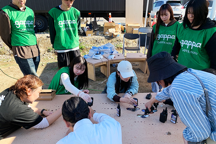 酒蔵跡地から掘り起こした黒瓦片や陶磁器片をベンチに埋め込む参加者 酒蔵跡地から掘り起こした黒瓦片や陶磁器片をベンチに埋め込む参加者
